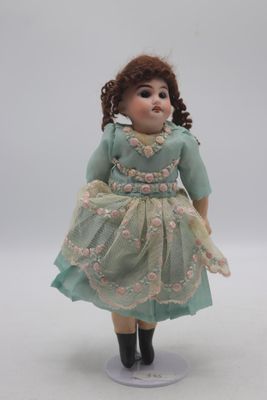 une petite poupée qui porte une robe et des bottes