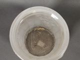 a white cup with a brown substance in it on a table