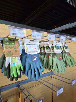 several pairs of gardening gloves hanging on a rack in a store