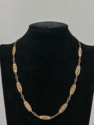a gold necklace on a mannequin neck with a black background
