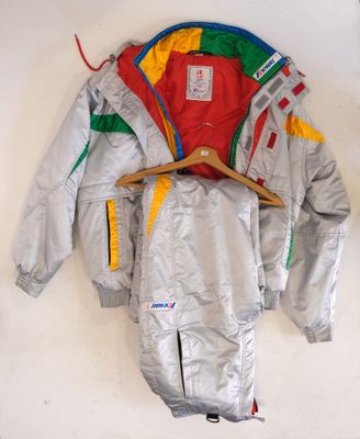 silver jacket with multicolored sleeves and a wooden hanger on a white wall