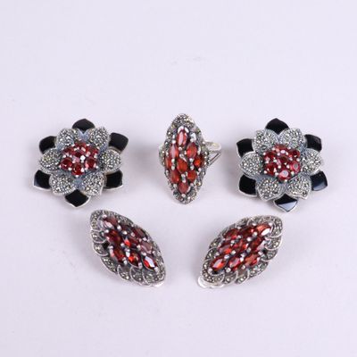 quatre bijoux en verre argenté et rouge posés sur un fond blanc