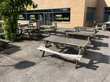 des tables et des bancs devant un bâtiment où est accrochée une enseigne indiquant « poisson frais et frites »