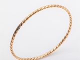 a gold bang bracelet with a twisted rope design