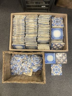 two baskets filled with blue and white tiles sitting on top of a carpet
