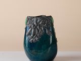 a blue vase sitting on a table with a brown wall in the background