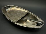 une assiette en argent sur laquelle repose une cuillère, posée sur un fond noir