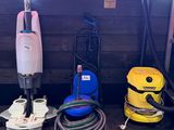 several vacuums and other cleaning equipment are lined up against a wall