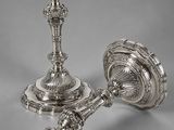 a pair of silver candlesticks on a grey background
