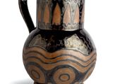 un vase brun et noir posé sur une surface blanche