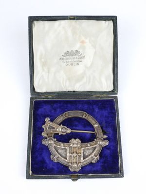 a silver broochle in a velvet case with a blue velvet lining