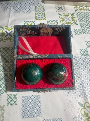two green balls in a red box on a table