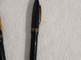 deux stylos et un portefeuille posés sur une surface blanche