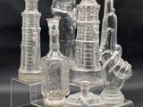 several clear glass vases and bottles are on a clear stand