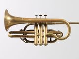a brass trumpet that is sitting on a white surface