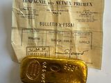 an old gold bar sitting on top of a piece of paper next to a receipt