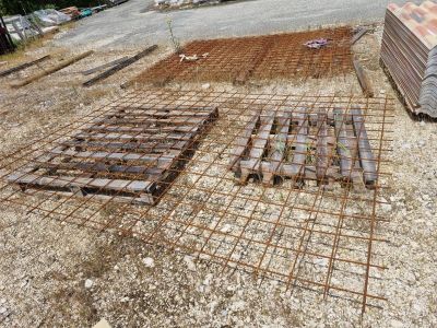 un tas de barres d'acier posé par terre à côté d'un tas de bois