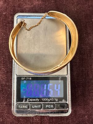 une balance numérique sur laquelle est posé un bracelet en or
