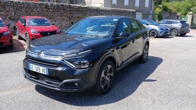 une voiture noire garée sur un parking près d'un mur de pierre