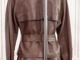brown leather trench coat on a mannequin stand in front of a white wall