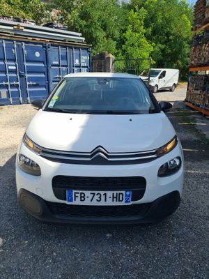the white car is parked in front of a stack of boxes