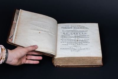 quelqu'un tient un vieux livre ouvert sur une surface noire