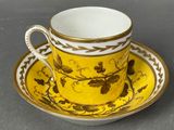 yellow and white coffee cup and saucer with a gold rim