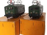 two green trains sitting on top of boxes on a white surface