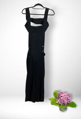 black dress hanging on a hanger next to a vase of flowers