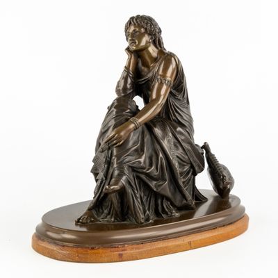 une statue en bronze représentant une femme assise sur un socle en bois