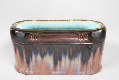 une jardinière marron et bleue posée sur une surface blanche