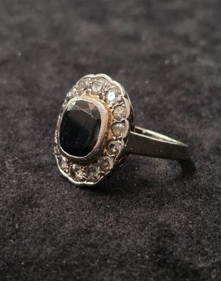 gros plan d'une bague avec une pierre noire entourée de diamants blancs