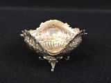 an antique silver plate with a shell in the center on a black surface