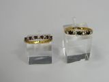 two rings with different colored stones on them sitting on top of a table