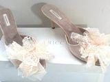 une paire de chaussures pour femme ornées de nœuds et de dentelle, posée sur une boîte blanche