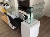 a desk with a glass top and a black chair in front of it