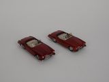 deux petites voitures rouges posées sur une surface blanche