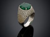 an emerald and diamond ring on a black surface