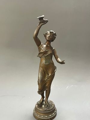 une statue en bronze représentant une femme tenant un oiseau dans la main