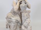 l'image d'une statue de femme assise sur un rocher