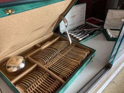 un coffret vert contenant de l'argenterie sur une table