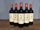 four bottles of red wine are lined up on a wooden table