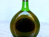 a green bottle with a hole in it on a table