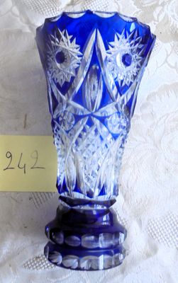 un vase en verre bleu posé sur une table, sur lequel est posée une note