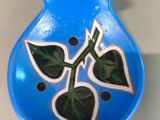 a blue vase with a green leaf on it