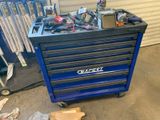 un chariot à outils bleu contenant des outils, dans un garage