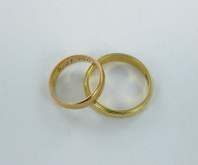 two gold wedding rings on a white surface