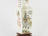 un vase blanc orné d'une peinture, posé sur un socle en bois