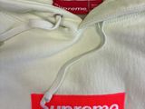 white supreme hoodie with red supreme logo on the chest