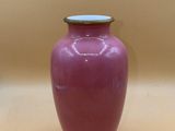 a pink vase with a silver lid on a table
